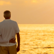 Panorama senior man and woman couple embracing at sunset or sunrise on a deserted tropical beach panoramic web banner