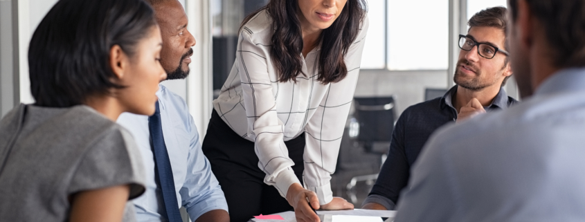 Team of multiethnic architects working on construction plans in meeting room. Engineers and designers discussing project in office. Businesswoman with business team in conference room working on blueprint.