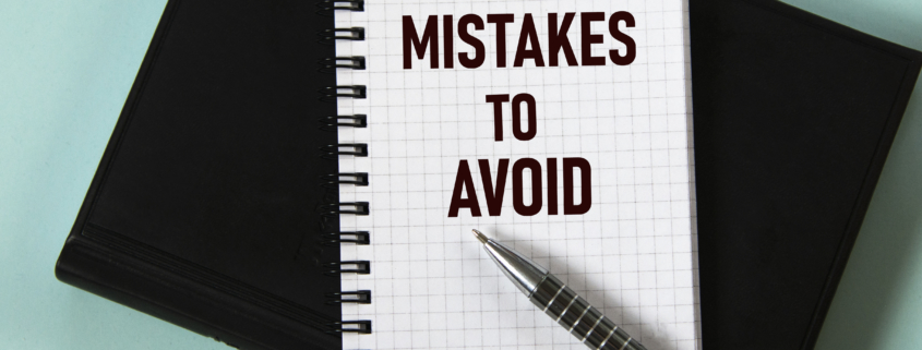 MISTAKES TO AVOID - words in a white notebook against the background of a black notebook with a pen. Business concept