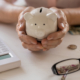 a person holding a piggy bank next to a calculator