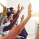 Group of people sitting down raising their hands